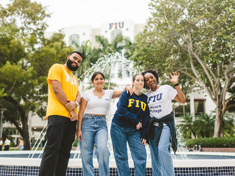 Four FIU students posing in front of the Graham Center fountain